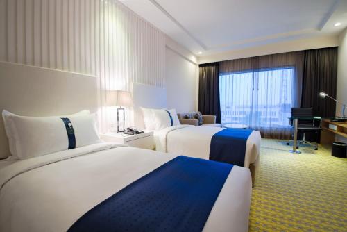 a hotel room with two beds and a desk at Holiday Inn Amritsar Ranjit Avenue by IHG in Amritsar