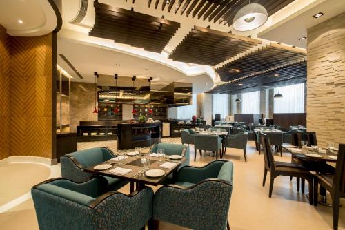 a restaurant with tables and chairs and a bar at Holiday Inn Amritsar Ranjit Avenue by IHG in Amritsar