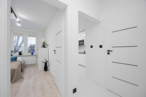 a white room with white cabinets and a bedroom at Wyjątkowy Apartament dla 4 osób by Noclegi Renters in Pruszków