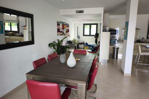 a dining room table with red chairs and a kitchen at Apartment with terrace close to the beach in Grosseto-Prugna