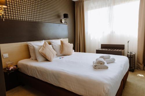 a hotel room with a large bed with towels on it at Clarion Aparthotel Toulouse Le Parc de l'Escale in Toulouse