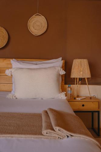 a bed with white pillows and a table with a lamp at Mia Agafay Resort in El Karia