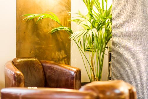 a brown leather chair sitting in front of a mirror at Hôtel Elite in Sion