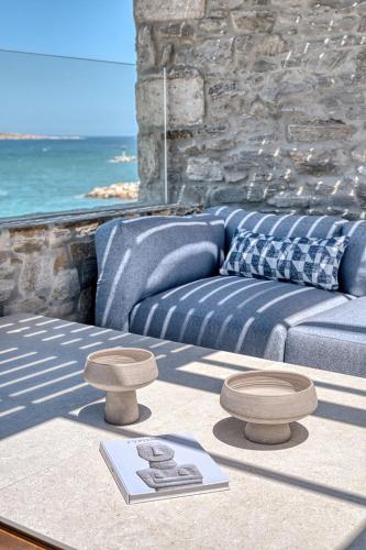 a living room with a blue couch and two stools at Avant Mar Paros in Naousa