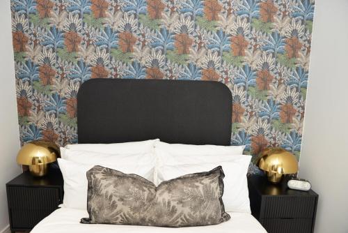 a bedroom with a bed with a black headboard and floral wallpaper at Ellipse Olive and Vine in Midrand