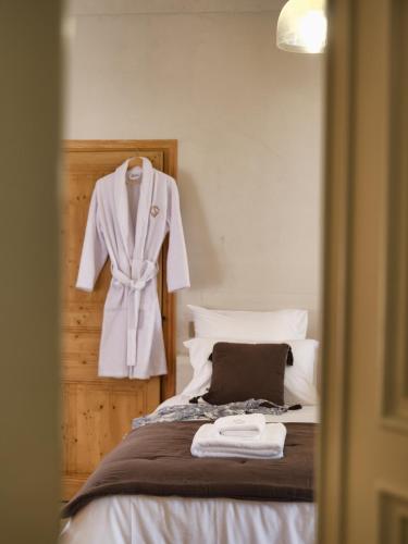 a white robe hanging on a wall next to a bed at Ferme Saint-Georges en Provence in Le Val