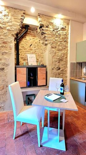 a table and chairs in a room with a stone wall at La Gatta in Montemerano