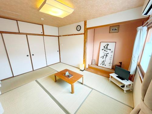a living room with a table and a tv at Guest House TAKAO in Tanabe