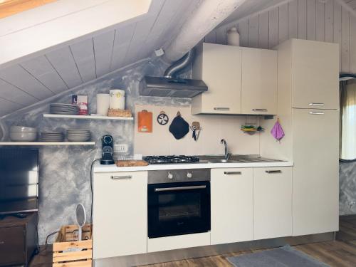 a kitchen with white cabinets and a stove at Terrazzo Panoramico - Vicino ad Asiago in Roana
