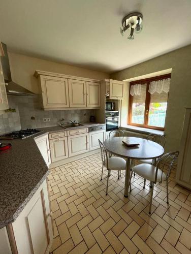 une cuisine avec une table et des chaises dans l'établissement Maison familiale au coeur des Vosges, à Aumontzey