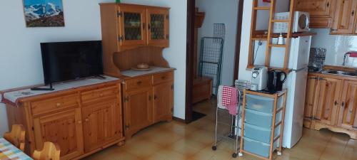 a kitchen with wooden cabinets and a flat screen tv at Casa 33 in Predazzo