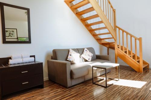 a living room with a couch and a staircase at Clarion Aparthotel Toulouse Le Parc de l'Escale in Toulouse
