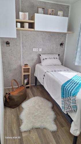 une chambre avec un lit, un sac à main marron et un tapis dans l'établissement Charmant mobil home camping Les Embruns, à Lège-Cap-Ferret