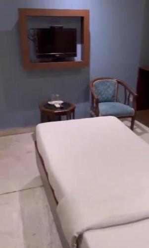a bedroom with a bed and a chair and a tv at Hotel GP Stays in Kolkata