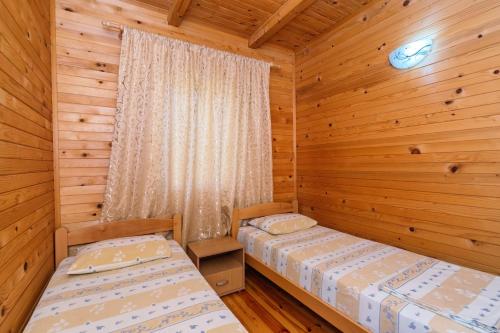 a bedroom with two beds in a log cabin at Apartments Aura in Utjeha