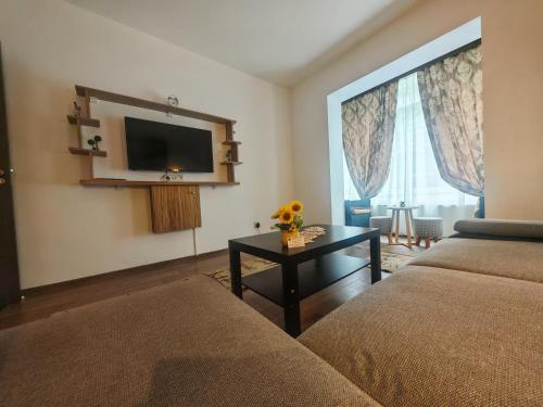 a living room with a couch and a tv and a table at Apartament Luca in Călimăneşti