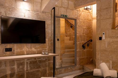 a bathroom with a shower and a television on a wall at Zekka House in Valletta
