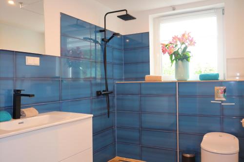 a blue tiled bathroom with a sink and a window at Ferienwohnung Am Deich in Kappeler Niederstrich