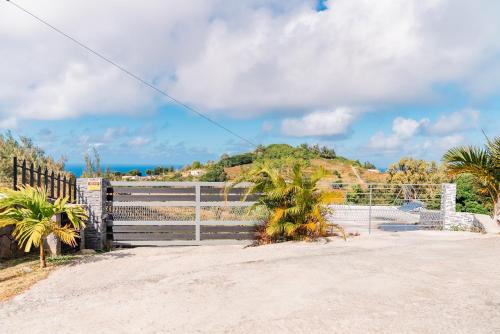 a gate with a fence and trees and the ocean at Villa Soleil de L'est in Port Mathurin