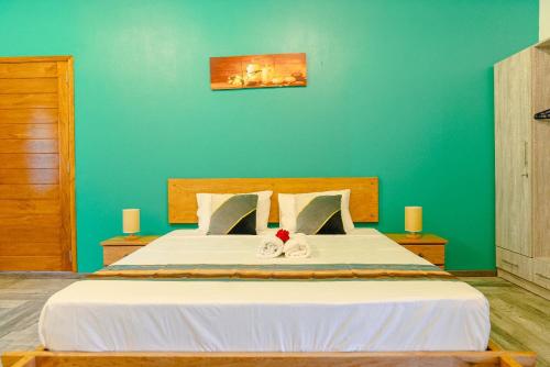 a bedroom with a large white bed with a green wall at Villa Soleil de L'est in Port Mathurin