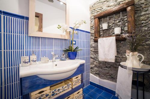 a blue tiled bathroom with a sink and a mirror at B&B Ca' La Vedescia in Teglio