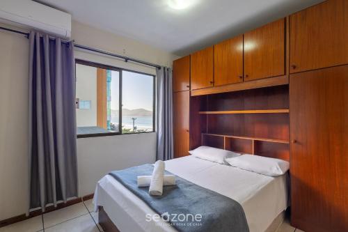 a bedroom with a bed with a large window at Apto Beira-Mar c/ Vista p/ Praia VTE0301 in Meia Praia