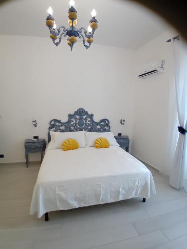 a white bedroom with a white bed with yellow pillows at EMARI HOME in Gaeta