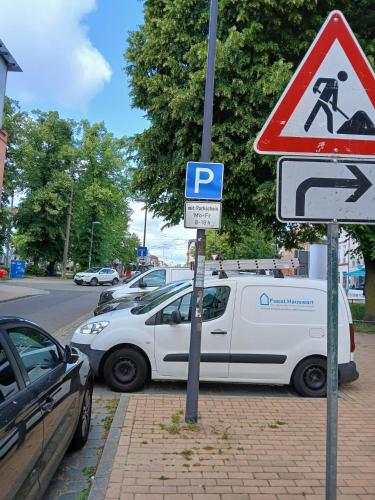 a white car parked next to a parking lot with street signs at Appartement mit Garten zentrumnah in Schwerin