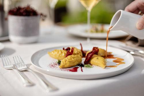 a plate of food on a table with a drink at Hotel Haus am Hang in Caldaro