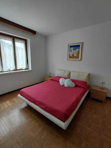 a bedroom with a large bed with a red blanket at Casa della nonna in Feltre
