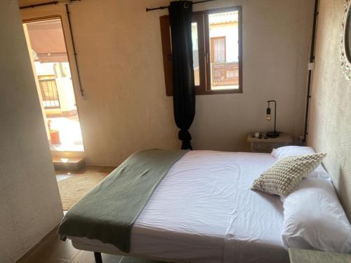 a bedroom with a white bed with a window at La Terreta hotel casa rural in El Brosquil