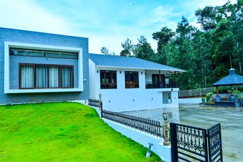 a house with a fence in front of a yard at Villa Vaasa Luxury Homestay in Avathi