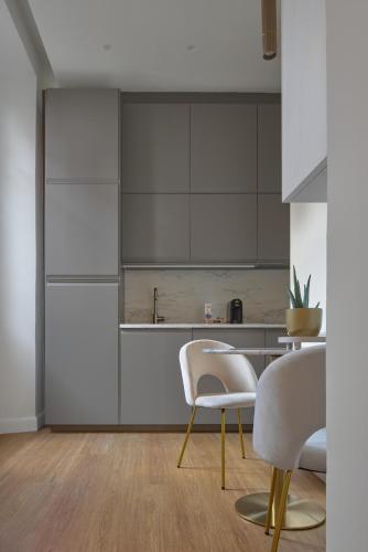 a kitchen with white cabinets and white chairs at Cosmo Lake City Apartments in Como