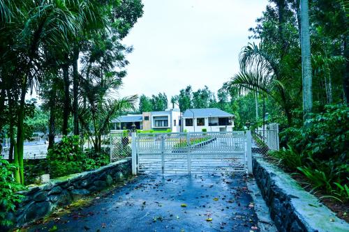 a white gate in front of a house with trees at Villa Vaasa Luxury Homestay in Avathi
