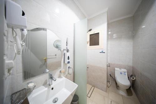 a white bathroom with a sink and a toilet at فندق ريحانة المكان من اورفانا in Makkah