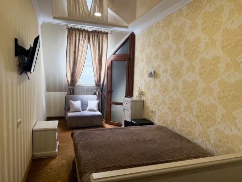 a bedroom with a bed and a chair and a window at VitaPark Stariy Dub in Truskavets