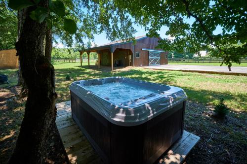 a hot tub sitting under a tree next to a building at Creekwalk Inn Bed and Breakfast with Cabins in Cosby