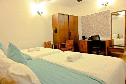 a hotel room with three beds and a desk and a room at Villa Vaasa Luxury Homestay in Avathi