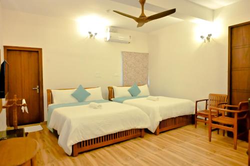 a bedroom with two beds and a ceiling at Villa Vaasa Luxury Homestay in Avathi