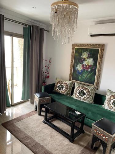 a living room with a green couch and a chandelier at Hotel La Perle du Sud in Ouarzazate