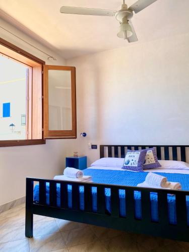 a bedroom with a bed with blue sheets and a window at Sulla Spiaggia in Marettimo