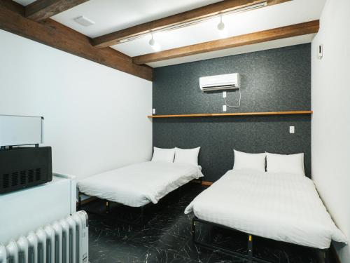 two beds in a room with a tv at Good Home Toyokawa in Hakodate