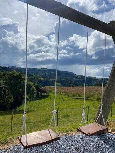 a swing seat with a view of a field at Chalé Vô Nono in Barracão