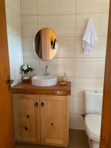 a bathroom with a sink and a toilet and a mirror at Chalé Vô Nono in Barracão