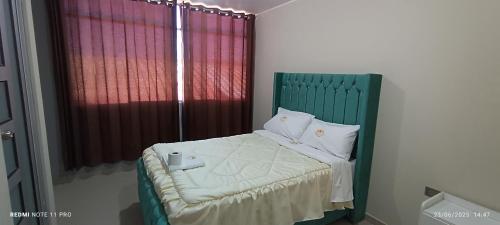 a bedroom with a green bed with red curtains at Hotel Mirador Wanka in Huancayo