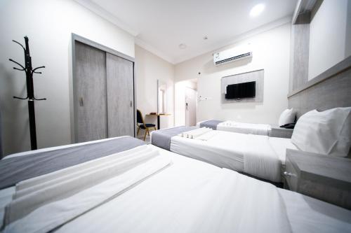 a white bedroom with two beds and a tv at فندق ريحانة المكان من اورفانا in Makkah