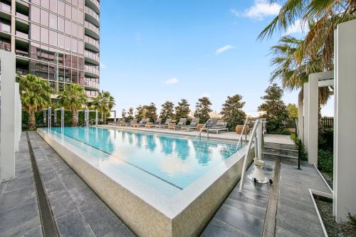 a large swimming pool with chairs and a building at Luxury VIP 4-Bedroom Townhouse in Port Melbourne in Melbourne