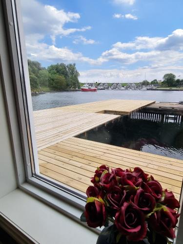 a bouquet of roses in a window with a view of a dock at Family-friendly Cabin with pier - Herdla to Bergen - 40 min in Herlø
