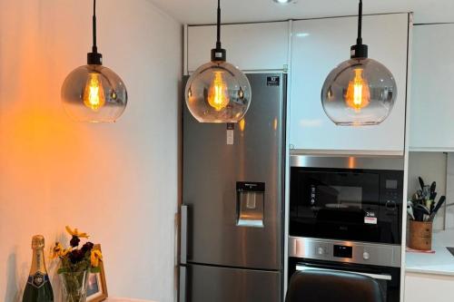 a kitchen with four pendant lights and a refrigerator at Sunset View 2BR Apartment - Beautiful London View & Free Parking in London