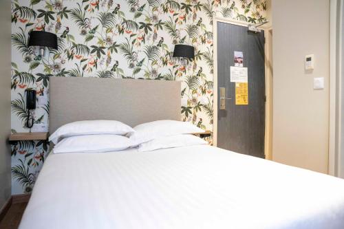 a bedroom with a white bed with a floral wallpaper at Verlain in Paris